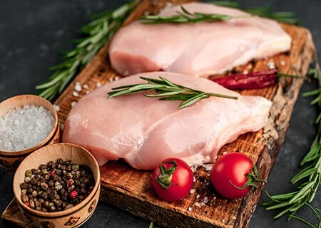 Pedaços de frango em tábua com ervas e tomates