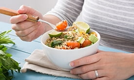 Pessoa comendo bowl com verduras e grãos