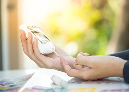 Pessoa medindo glicemia no dedo com aparelho