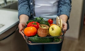 Pessoa segurando pote de vidro com diversos alimentos como frutas e vegetais