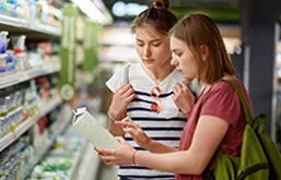 Mulheres no supermercado observando rótulo de alimento