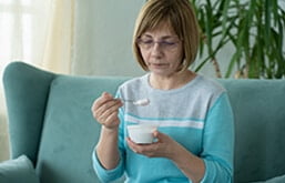 Mulher sentada no sofá comendo iogurte
