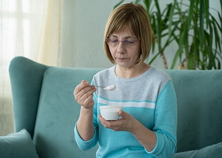 Mulher sentada no sofá comendo iogurte