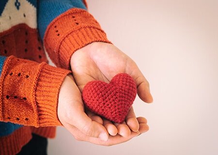 Mão segurando miniatura de coração de crochê