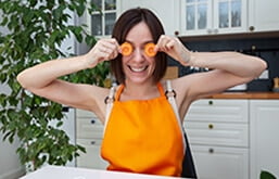 Mulher segurando rodelas de cenoura em frente aos olhos