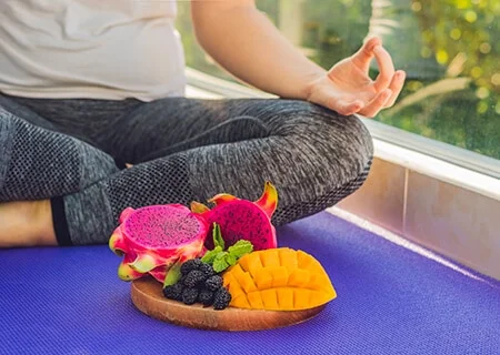 Pessoa meditado atrás de prato com frutas