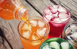 Copos com refrigerantes coloridos - laranja, vermelho e verde, com pedras de gelo