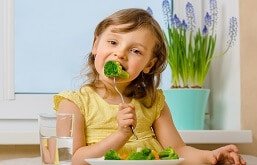 Menina comendo brócolis