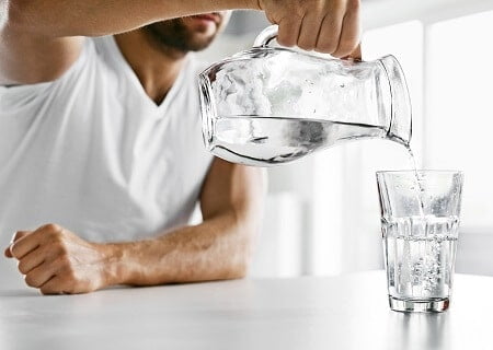 Homem colocando água em um copo de vidro