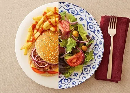 Prato dividido com metade de um hambúrguer com fritas e metade de uma salada