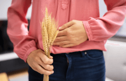 Pessoa segurando ramos de trigo e a mão na barriga