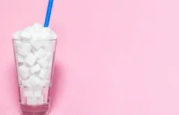 Copo transparente com torrões de açúcar e um canudo azul