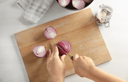 Mãos cortando cebola em uma tábua