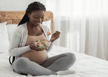 Gestante comendo salada para evitar o risco de pré-eclâmpsia