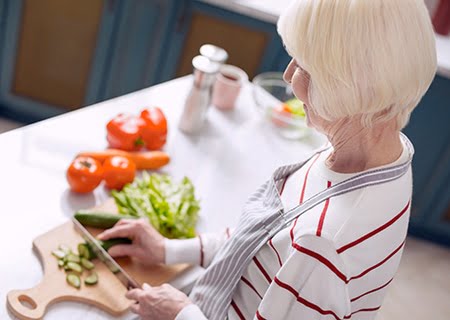 Mulher idosa picando pepino na cozinha