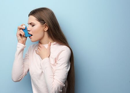 Mulher inalando bombinha de asma