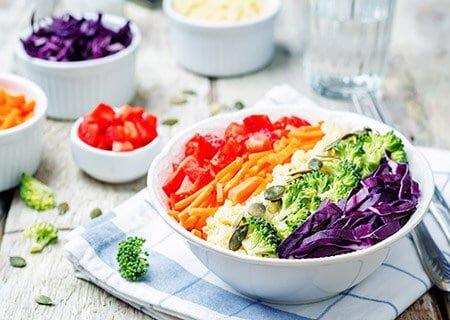 Tigela com vegetais como tomate, cenouras, brócolis e repolho-roxo. Uma sugestão de como montar um prato colorido.