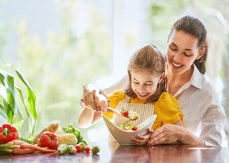 Mãe e filha preparando salada nutritiva completa