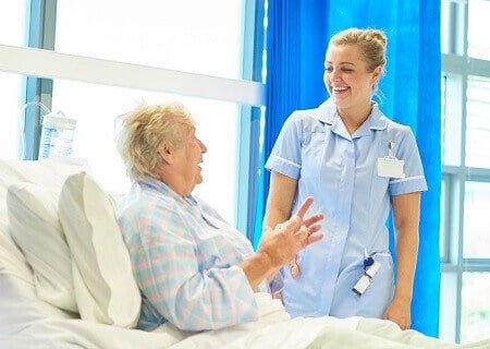 Paciente idosa conversando com médica no leito hospitalar