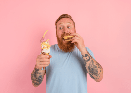 Homem barbudo e tatuado comendo hambúrguer e tomando sorvete